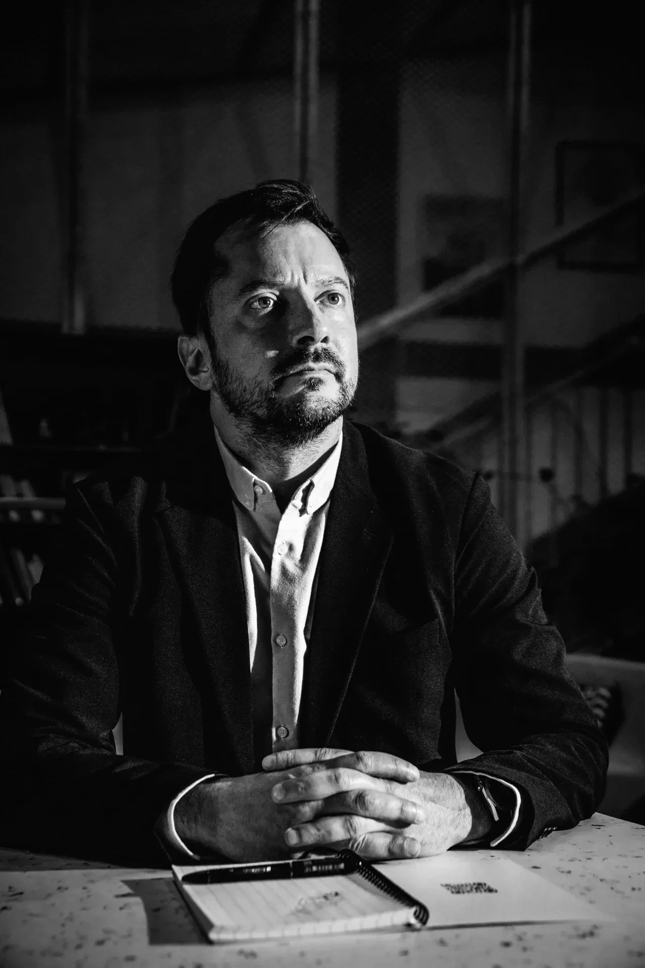 Victor Mallet, consultant en cybersécurité, en noir et blanc, assis à une table, mains jointes, regard levé vers un point hors du cadre